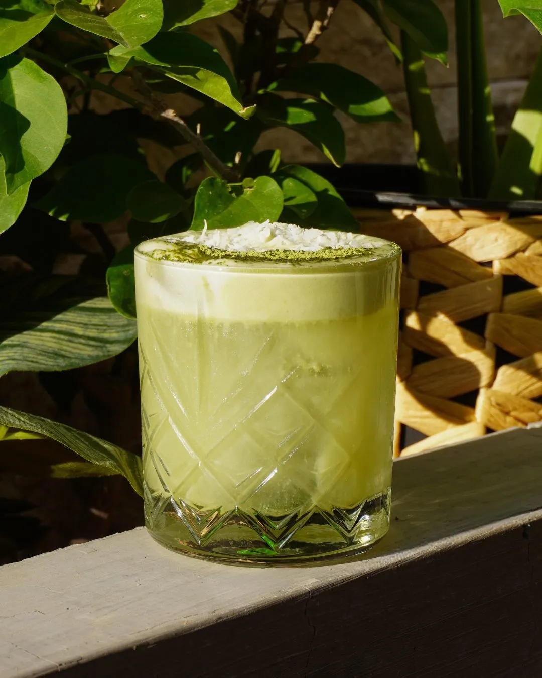 Matcha latte de Sabina servido en vaso de vidrio, entre plantas